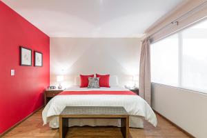 Un dormitorio con una pared de acento rojo y una cama en Suites Copérnico Polanco Anzures, en Ciudad de México