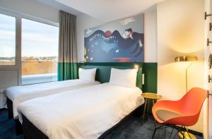 una habitación de hotel con 2 camas y una silla en ibis Styles Pforzheim en Pforzheim