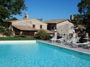 a pool in front of a house with chairs at Castello di Acera in Campello sul Clitunno