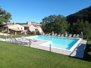 a large swimming pool with chairs and a house at Castello di Acera in Campello sul Clitunno