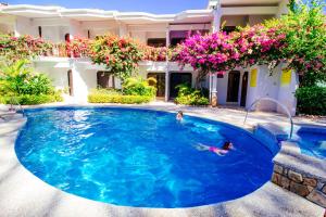 a swimming pool in front of a house with flowers at Hotel Giada in Sámara
