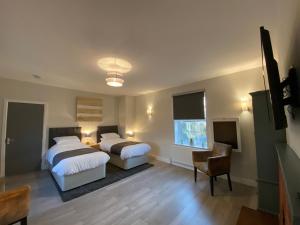 een slaapkamer met 2 bedden, een stoel en een raam bij The Fordham Inn in Sharnbrook