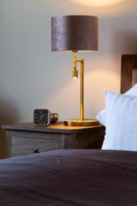 a bed with a lamp and a clock on a table at Hofgut Holzmuhle in Germersheim