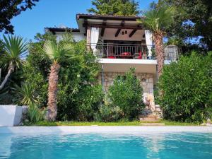 une maison avec des palmiers en face d'une piscine dans l'établissement Artistic Beach House with Pool, à Jadranovo