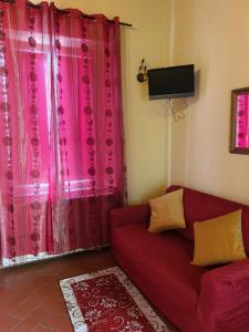 a living room with a red couch and pink curtains at Window To The Tower in Pisa