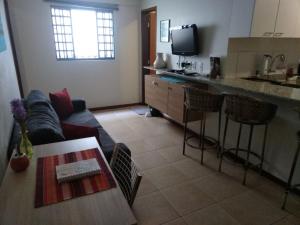 a living room with a couch and a table and a kitchen at Ipê Rosa Apartamento in Brasilia
