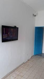 Une télévision à écran plat est installée sur un mur à côté d'une porte bleue. dans l'établissement OCEAN-SI MAnsion, à Kribi