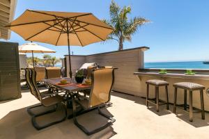 eine Terrasse mit einem Tisch, Stühlen und einem Sonnenschirm in der Unterkunft 358 Front Street in Avila Beach