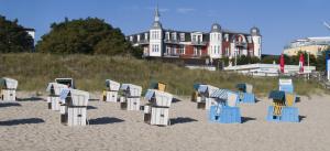 uma fila de cadeiras de praia na areia numa praia em Strandhotel Preussenhof em Zinnowitz