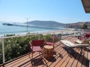 a balcony with chairs and a table and the ocean at 196 Front Street in Avila Beach