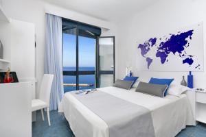una camera bianca con un grande letto e una mappa del mondo sul muro di Panorama Palace Hotel a Meta
