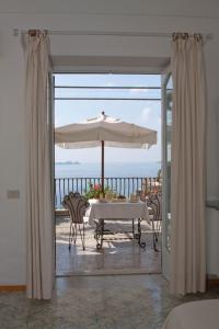 a dining room table with an umbrella and a balcony at Villa Rosa in Positano