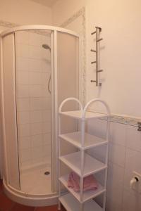 La salle de bains est pourvue d'une douche et d'étagères blanches. dans l'établissement Le Soleil, à Campo nell'Elba