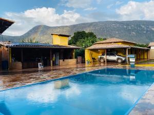 a swimming pool in front of a house with a car at Vila Dos Sonhos Lapinha in Santana do Riacho