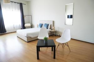 a bedroom with a bed and two white chairs at Oporto Trindade Residence in Porto