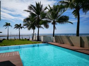 a swimming pool with palm trees and the ocean at Brizo Hotel and Beach Resort Bataan in Morong