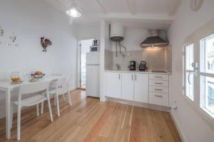 a white kitchen with a white table and a white refrigerator at Home in one of Évora´s most historical squares in Évora