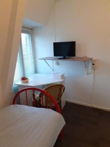 a room with a bed and a desk with a television at Hostel Pension Tivoli in Groningen