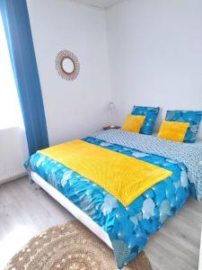 Schlafzimmer mit einem Bett mit blauer und gelber Bettwäsche in der Unterkunft GITE LE SAINT-AMOUR in Saint-Amour