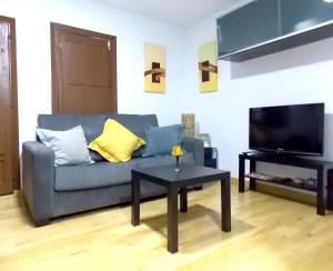 uma sala de estar com um sofá azul e uma mesa em Apartamentos Capuchinas em Plasencia