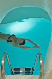 a woman laying in a swimming pool in a blue water tunnel at Art Maisons Oia Castle in Oia