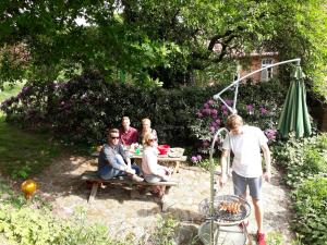 eine Gruppe von Menschen, die an einem Tisch im Garten sitzen in der Unterkunft Neulandhof Spöring in Walsrode