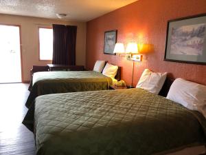 2 camas en una habitación de hotel con paredes de color naranja en Lone Star Inn, en Cisco