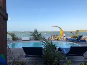 een zwembad met stoelen en de oceaan op de achtergrond bij Cabana Chic Sunrise in Tatajuba