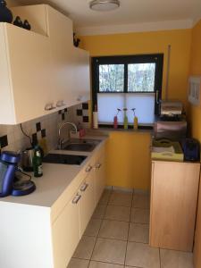 eine Küche mit weißen Schränken, einem Waschbecken und einem Fenster in der Unterkunft Ferienwohnung auf dem Kutzenberg in Altendorf