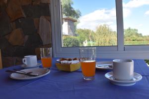 una mesa con un paño de mesa azul con platos y vasos de zumo de naranja en Apartdora en Yacanto