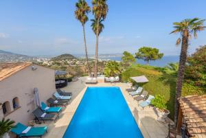 a swimming pool with lounge chairs and palm trees at La Sarriette in Théoule-sur-Mer