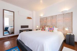 a bedroom with a large white bed and a mirror at epicenter ORIENT in Ponta Delgada