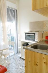 狄奧尼修海灘的住宿－Zoi Apartments，厨房配有水槽、微波炉和桌子