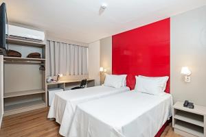 2 camas en una habitación de hotel con una pared roja en Slim Guarapuava en Guarapuava