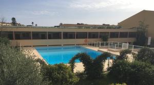 - un bâtiment avec une grande piscine en face dans l'établissement Meublés de Tourisme Beaulieu, à Beaulieu-sur-Mer