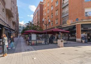 eine Stadtstraße mit Leuten, die eine Straße mit Gebäuden entlanglaufen in der Unterkunft BILBAO METROPOLITAN by STAYNN APARTMENTS in Bilbao
