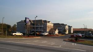 a parking lot with a large building with cars parked at InTown Suites Extended Stay Savannah GA in Savannah