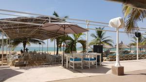 a beach with tables and chairs and an umbrella at Safari Village - Case73 in Saly Portudal