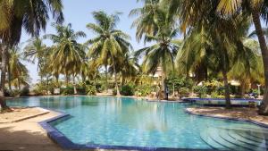 a swimming pool with palm trees in a resort at Safari Village - Case73 in Saly Portudal