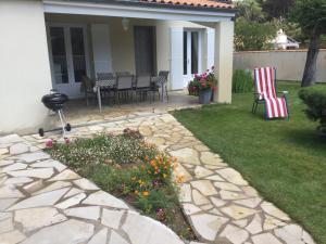 a patio with chairs and flowers in a yard at Maison bercée par le bruit de la mer île de ré in Sainte-Marie-de-Ré