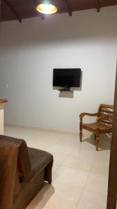 uma sala de estar com uma televisão, um sofá e uma cadeira em Loft Pireneus 1 em Pirenópolis