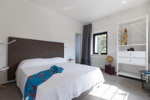 - une chambre blanche avec un grand lit blanc et une fenêtre dans l'établissement Gallo Fino, à Ricadi