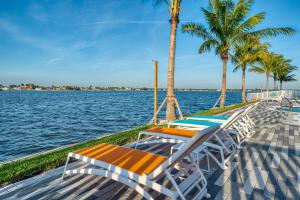 a row of lounge chairs and palm trees on a dock at FUSION Resort Waterfront Suites in St Pete Beach +74 photos