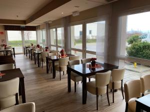 - une salle à manger avec des tables, des chaises et des fenêtres dans l'établissement REGIOHOTEL Leipzig West, à Schkeuditz