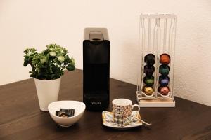 a table with a coffee maker and cups and a vase at Casas da Avó Bia in Lagos