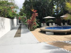 a patio with a pool and chairs and an umbrella at La Perlita in Jacó