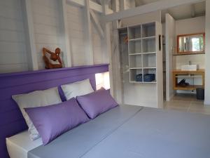 a large bed with purple pillows in a room at Caraïbes Cottages Jellyfish piscine privée a 900m de la plage de Grande Anse in Deshaies +29 photos