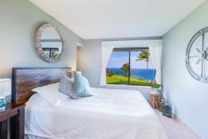 a bedroom with a bed and a window with the ocean at Oceanfront Condo with panoramic views! in Princeville