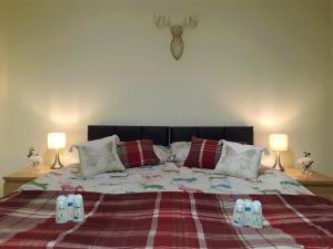 a bedroom with a bed with a blanket and two lamps at Airdrie Apartments in Airdrie