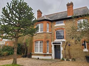 ein Backsteinhaus mit einem Baum davor in der Unterkunft Sleeplicity London Heathrow in Feltham